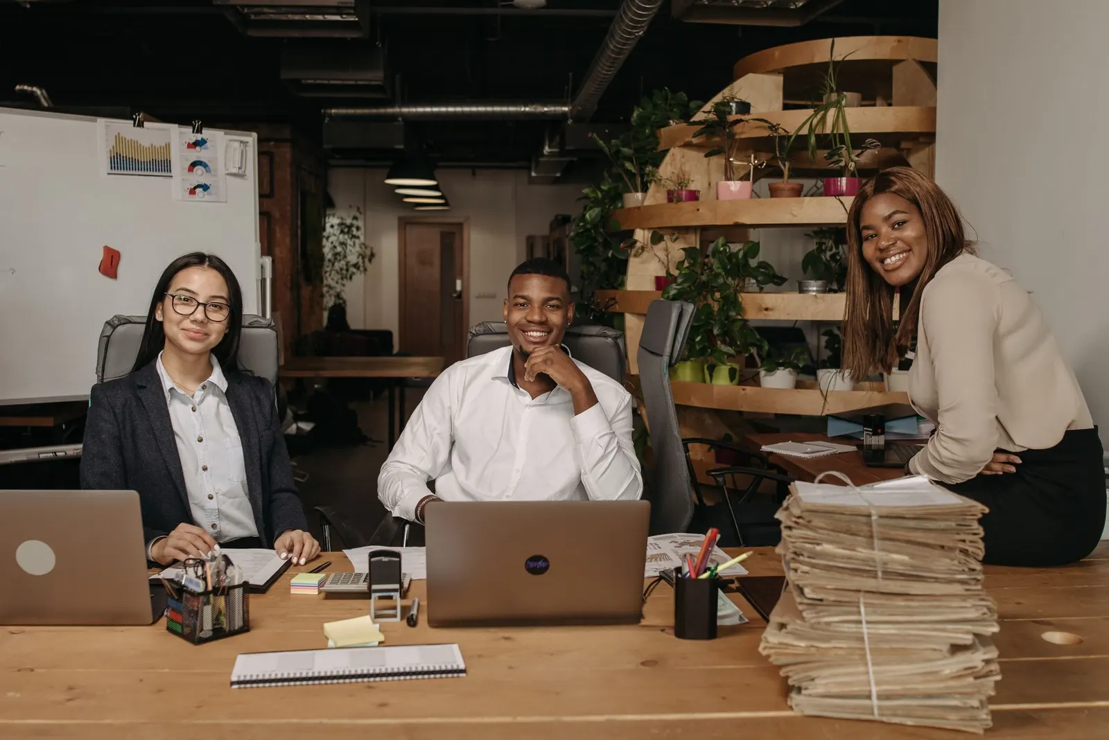 A small team of colleagues smiling and working together around a laptop in a bright office.